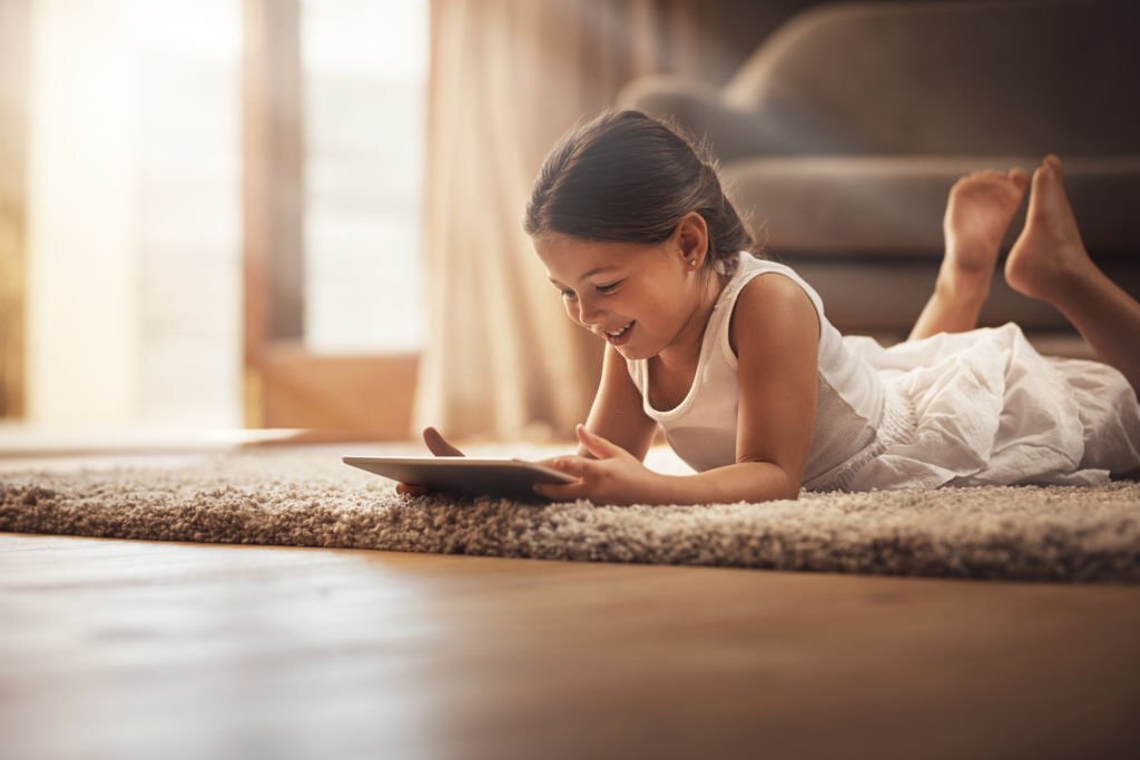 Shot of an adorable little girl using a digital tablet on the floor at home